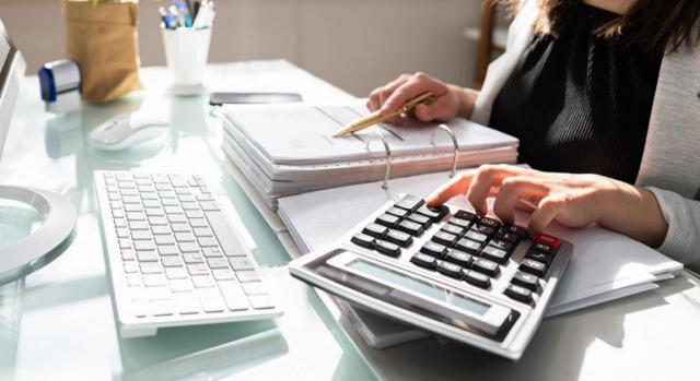 Presentación e información a revelar en los estados financieros NIIF 18 'Presentación e información a revelar en los estados financieros'. Imagen de una chica en un escritorio con una calculadora y un teclado de ordenador