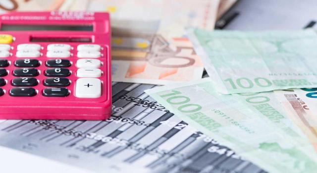 Caso practico resuelto aplicado a la Consulta 4 del BOICAC 136 Cuestiones relacionadas con el cobro de dividendos desde el punto de vista del socio. Imagen de una calculadora rosa sobre unos billetes de 100 euros