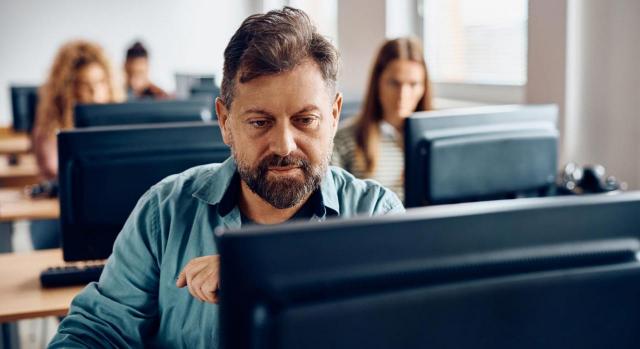 Vídeos educativos sobre el Estándar Voluntario de Informes de Sostenibilidad para pymes no cotizadas Vídeos educativos sobre el Estándar Voluntario de Informes de Sostenibilidad para pymes no cotizadas. Hombre de mediana edad trabajando en un ordenador de mesa
